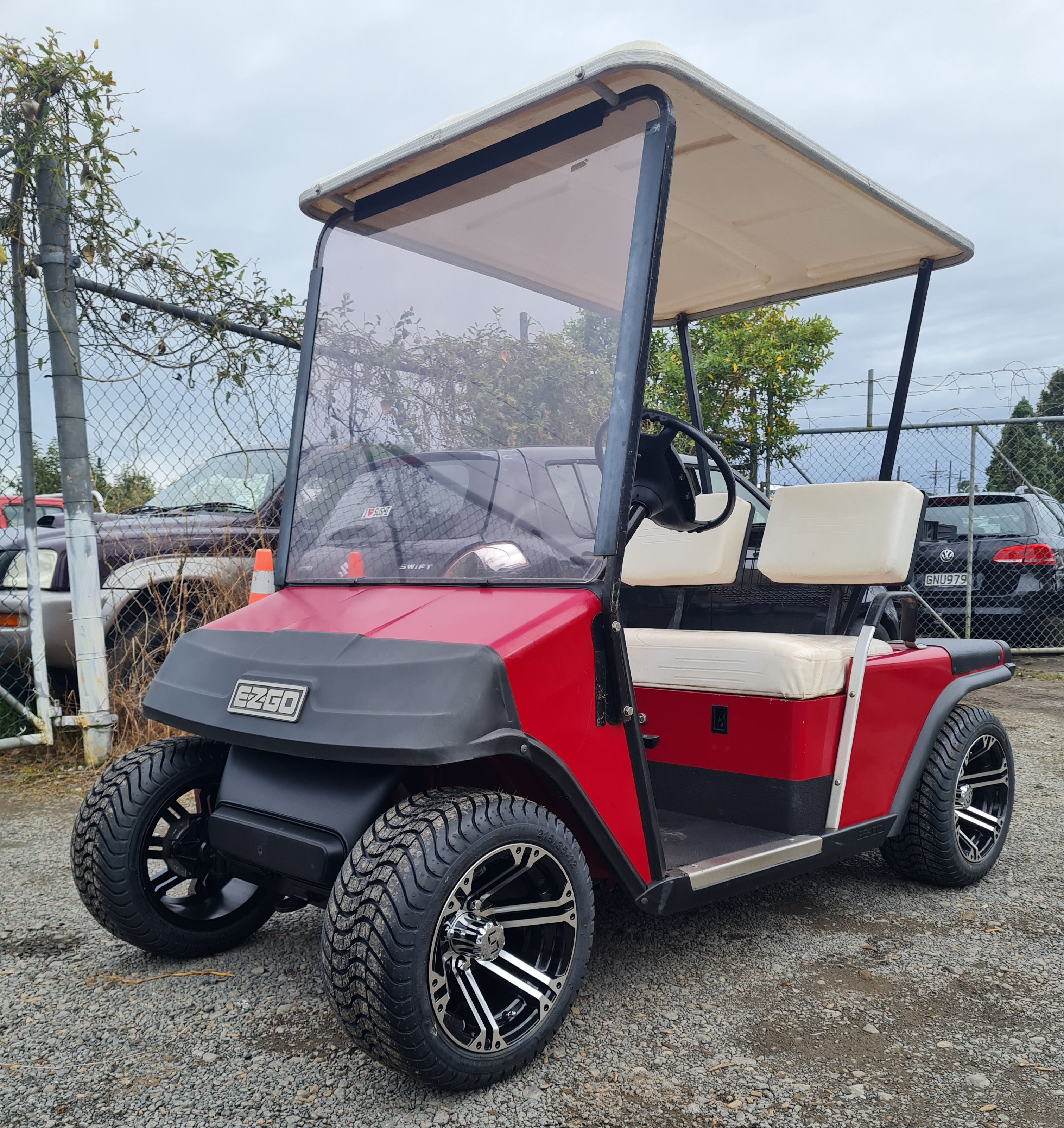 Red EZGO TXT golf cart with lift kit and chrome-black mag wheels