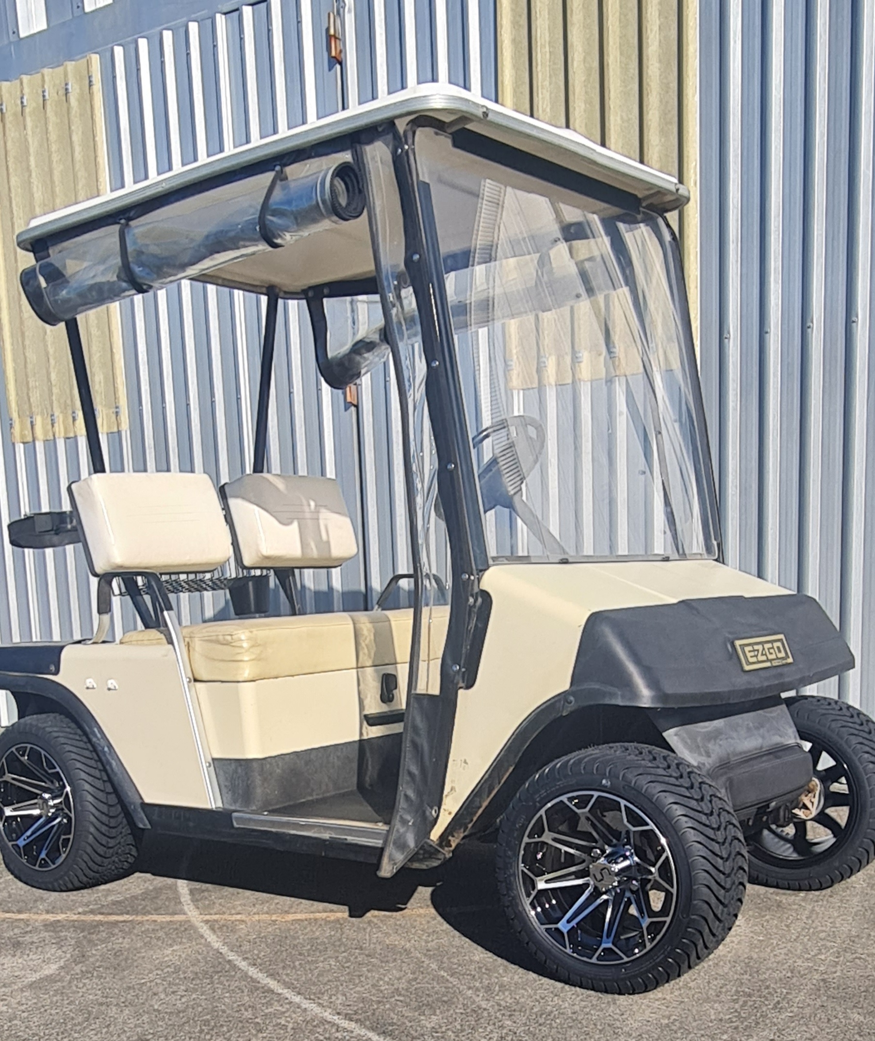 Cream EZGO RXV golf cart with blue-black mag wheels